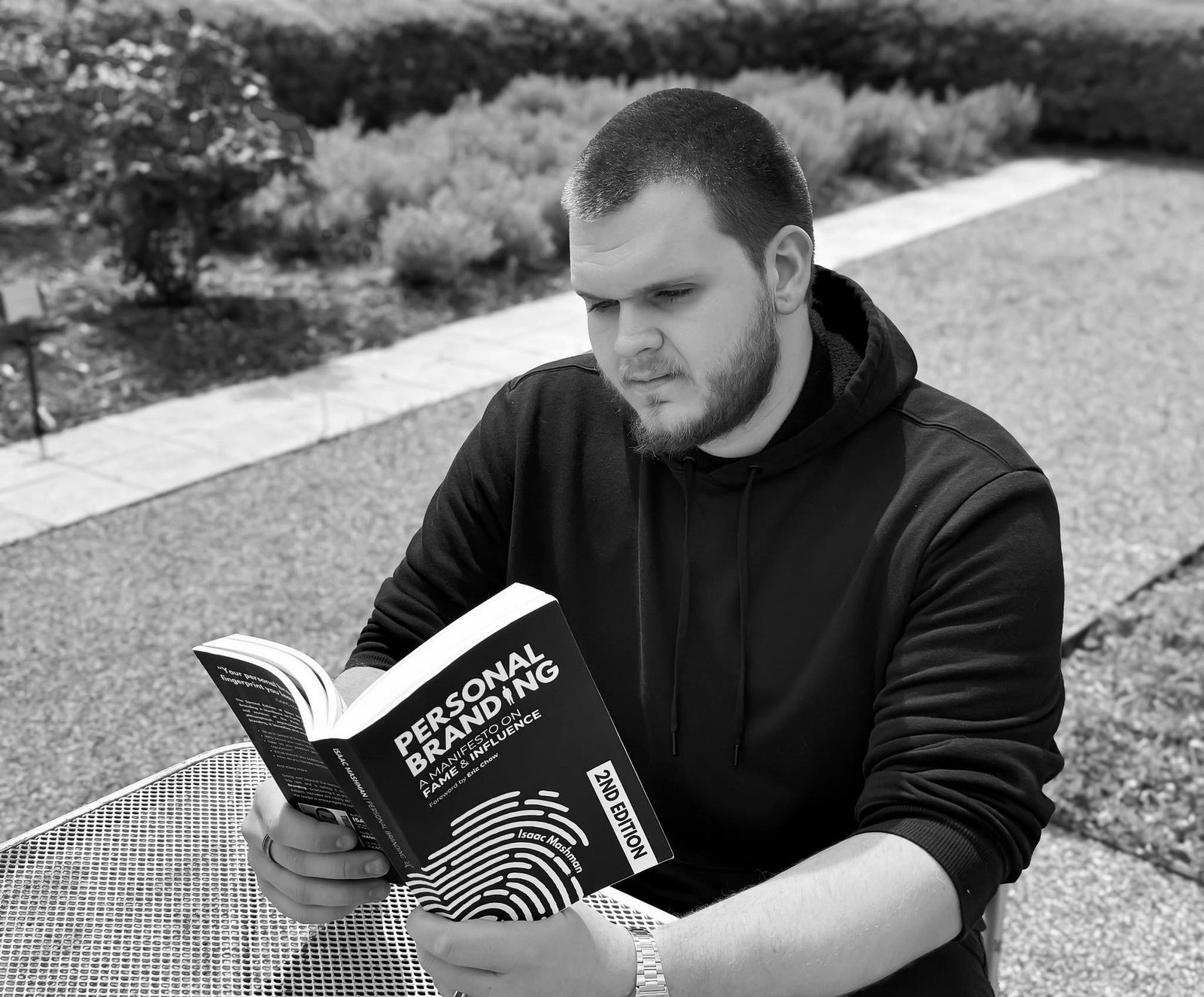 Isaac Mashman reading the Second Edition of Personal Branding: A Manifesto on Fame and Influence at an outdoor table