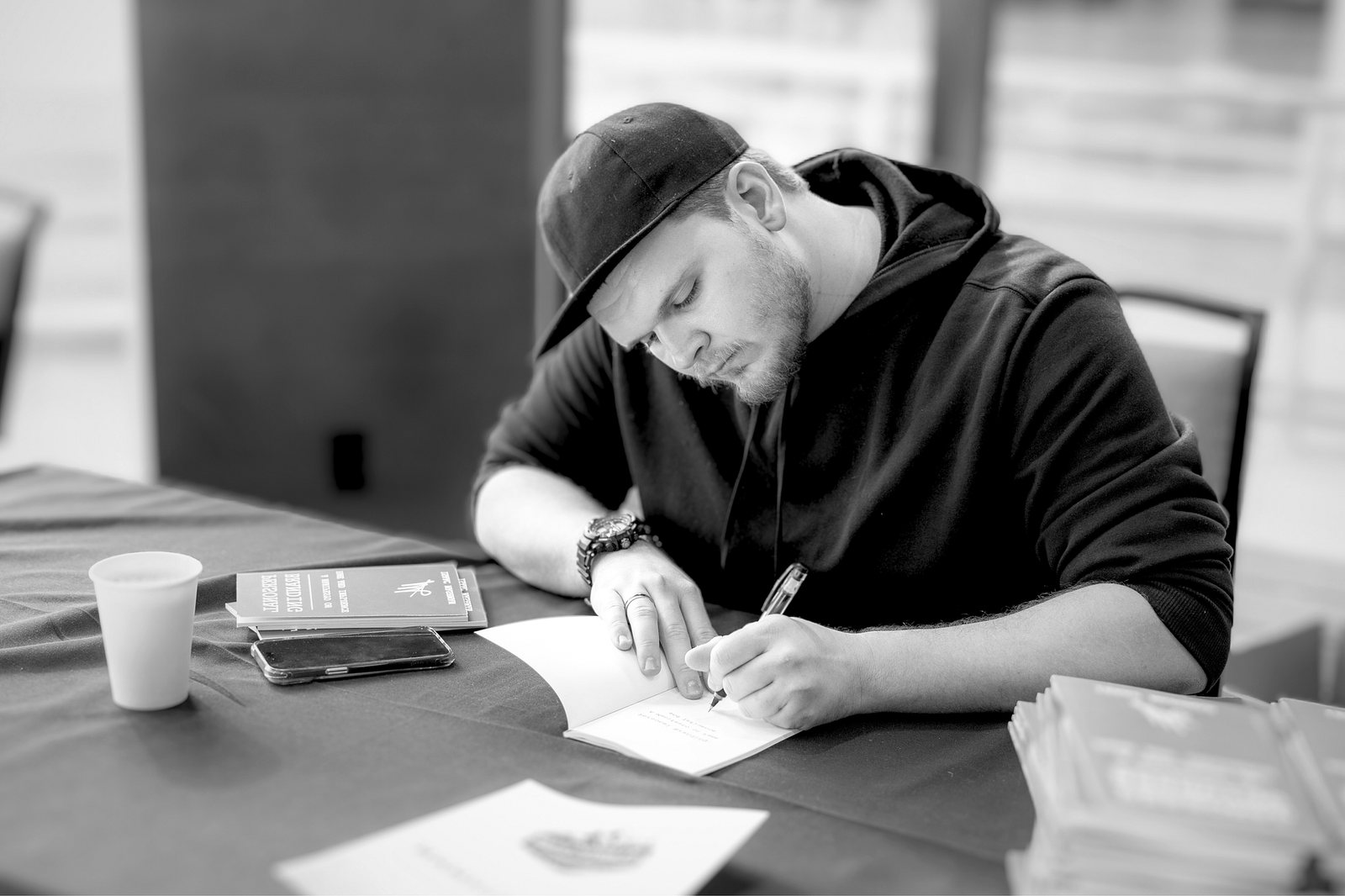 Isaac Mashman signing a copy of his book at a table in Denver, 2024