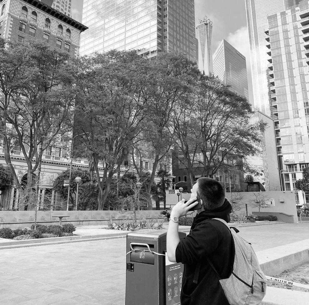 Isaac Mashman in downtown Los Angeles, phone to his ear, looking up at the skyscrapers