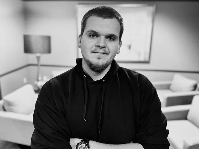 Isaac Mashman in a black hoodie, arms crossed, in a lounge
