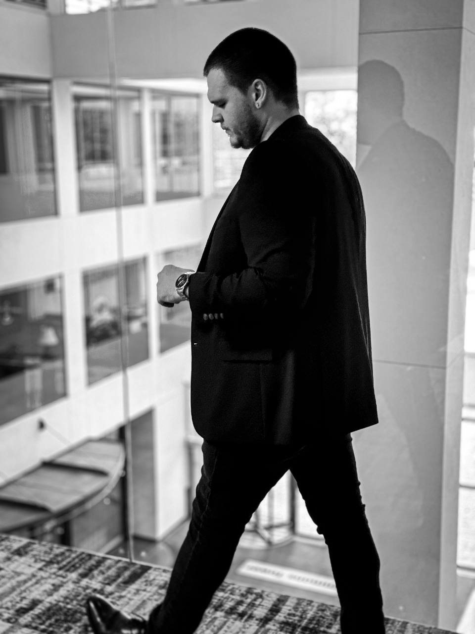 Isaac Mashman checking his watch as he walks along an atrium balcony